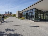 the large building has glass doors and windows in it's windows is next to a park