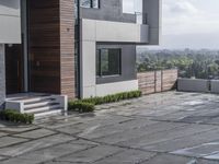 the courtyard outside of a modern home with stairs leading up to the patio area with plants and bushes on either side of the house