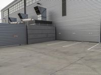 a large grey hangar with lots of windows in front of the building by itself in a parking lot