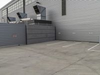 a large grey hangar with lots of windows in front of the building by itself in a parking lot