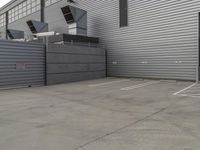 a large grey hangar with lots of windows in front of the building by itself in a parking lot