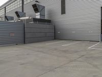 a large grey hangar with lots of windows in front of the building by itself in a parking lot