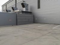 a large grey hangar with lots of windows in front of the building by itself in a parking lot