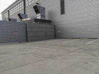 a large grey hangar with lots of windows in front of the building by itself in a parking lot