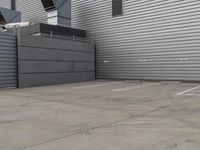 a large grey hangar with lots of windows in front of the building by itself in a parking lot