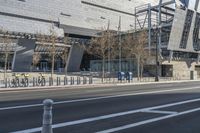 a building is standing next to the road next to a curbed area and bike racks