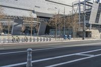 a building is standing next to the road next to a curbed area and bike racks