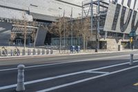 a building is standing next to the road next to a curbed area and bike racks