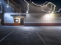 a building in a parking lot with lightning coming from the window and lights all around