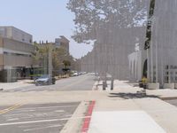 an empty street that has cars driving on it and a building in the distance with trees growing from the cement