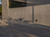 a skateboarder is riding an empty concrete court as seen from the street side