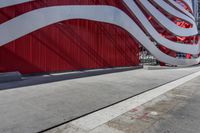 there is an american flag on the side of this building by the sidewalk area,