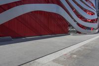 there is an american flag on the side of this building by the sidewalk area,