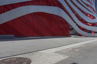 there is an american flag on the side of this building by the sidewalk area,