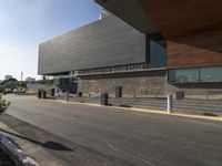 the large building is next to the walkway near a road leading to a building with a metal fence