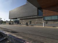 the large building is next to the walkway near a road leading to a building with a metal fence