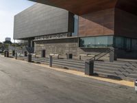 the large building is next to the walkway near a road leading to a building with a metal fence