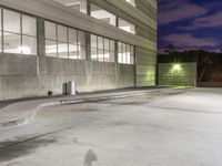 a building with a person walking in the parking lot outside at night by a fire hydrant