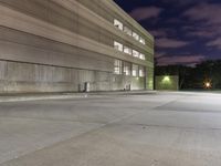 a building with a person walking in the parking lot outside at night by a fire hydrant