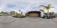 a 360 - degree panoramic view of a modern home garage and driveway with palm trees