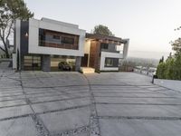 the exterior and landscape of a modern house in los angeles, california with stone and wood