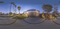 a fisheye view of the front yard and walkway of a residential complex, with a car parked in the driveway next to trees