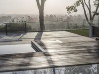 there is an outdoor pool and deck overlooking the city, with trees and bushes surrounding it