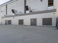 two air ducts sit on the side of a building with white siding and windows