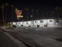 an empty motel with no traffic sign and palm trees in the background at night sky