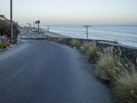 a man is driving a motorcycle on the side of an empty road along the beach