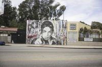 large mural depicting a portrait of prince and holding a cigarette in a street corner with buildings