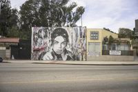 large mural depicting a portrait of prince and holding a cigarette in a street corner with buildings