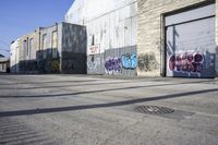 a person rides a skateboard near graffiti covered buildings along the street in a city