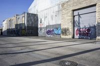 a person rides a skateboard near graffiti covered buildings along the street in a city
