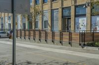 a bus riding by a fence on the side of a road next to a building