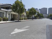 an arrow is painted on the side of a street in a city with tall buildings and parked cars