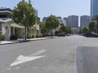 an arrow is painted on the side of a street in a city with tall buildings and parked cars