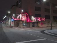 street lights illuminate the exterior of a modern building at night with a neon sign for an electrical station