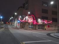 street lights illuminate the exterior of a modern building at night with a neon sign for an electrical station