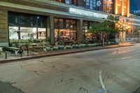 an empty sidewalk next to a restaurant and trees on the sidewalk and a busy street