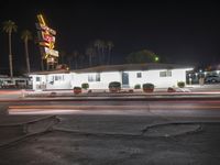 a night shot of an old motel at a busy intersection with traffic in front of it