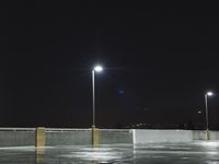 an empty parking lot has lights on and on, lights in the dark sky above
