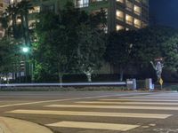 a street light on the corner of a large city block at night with buildings and trees