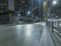 an empty city street during the night with no traffic and many lights on it,