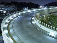 the curve of a freeway with traffic on it's sides in the dark night sky