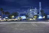 an industrial factory lit up at night with lights and parking lot in front of it