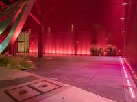 a red light shines brightly on an empty building area with plants on the ground