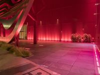 a red light shines brightly on an empty building area with plants on the ground