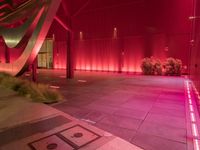 a red light shines brightly on an empty building area with plants on the ground