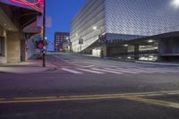 an empty city street with some tall buildings in the background and lights at the side